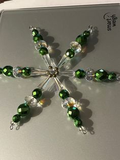 a snowflake made out of green and clear beads