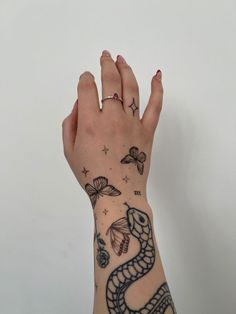 a woman's hand with tattoos on it and a snake tattoo on the wrist