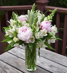 a vase filled with pink and white flowers on top of a wooden table