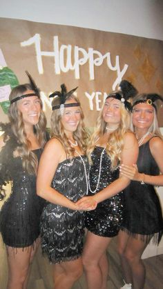 four women dressed in black and silver posing for a photo with a happy new year sign behind them