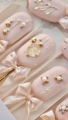 some pink and gold decorated cookies in a box with bows on it's sides