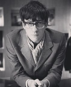 black and white photograph of man in suit sitting at table with hand on hipster's lap