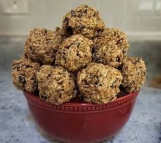 a red bowl filled with oatmeal cookies on top of a granite counter