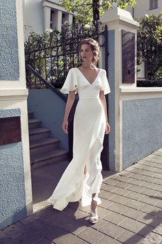 a woman in a white dress is walking down the street with her hand on her hip