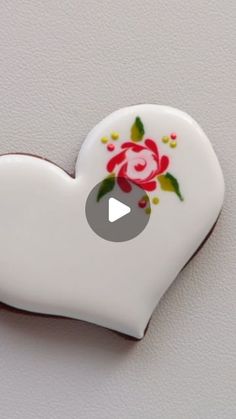 a white heart with a rose painted on it