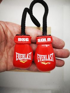 two red boxing gloves are being held by someone