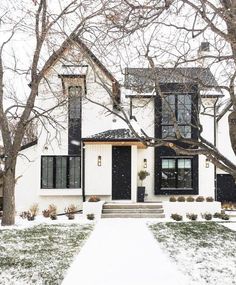 a white house with black shutters and snow on the ground