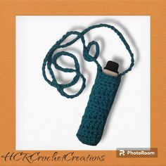 a blue crocheted bottle with a black cap on it's side and a string around the neck