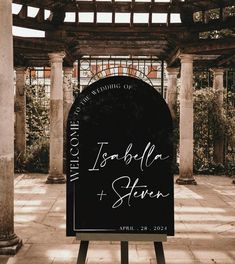 a black and white wedding sign sitting on top of a wooden bench in front of a building