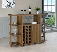 a wooden bar with wine glasses and bottles on the top shelf in front of a window