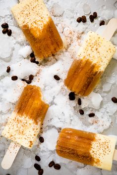 three popsicles are sitting on some ice with coffee beans and cinnamon sprinkles