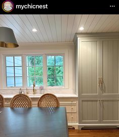 a large kitchen with white cabinets and wood flooring, along with a dining room table