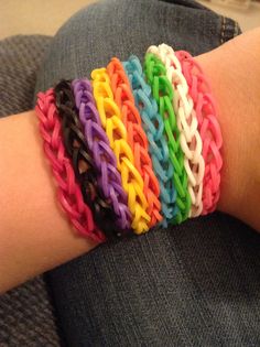 a person's arm is covered with multicolored bracelets that are attached to each other