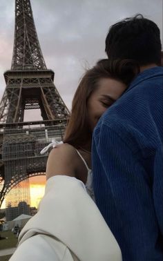 a man and woman standing in front of the eiffel tower