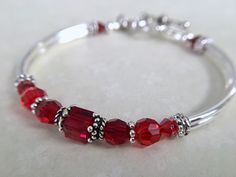 Ruby red bangle bracelet - perfect to gift for your loved ones birthday! Very comfortable and stylish. Message me to change the colors... ~ 6mm garnet swarovski crystal ~ 4mm and 6mm garnet and siam swarovski crystals ~ 6mm sterling silver bead caps ~ silver plated tube bead bangles and toggle Click here to return to my shop's homepage: https://www.etsy.com/shop/beadedjewelryforyou?ref=simple-shop-header-name&listing_id=604235185 Adjustable Red Birthstone Bracelet, Nickel-free Red Jewelry For Birthdays, Personalized Red Beaded Bracelets For Birthday, Red Bracelet For Valentine's Day Birthday, Personalized Red Jewelry For Birthday Gift, Adjustable Red Bracelets For Anniversary, Personalized Red Bracelet For Birthday Gift, Red Birthstone Jewelry For Birthday, Red Birthstone Jewelry For Birthdays