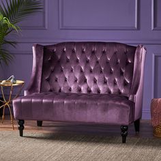 a purple couch sitting on top of a wooden floor next to a potted plant