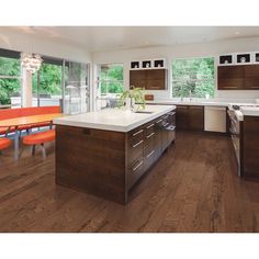 a large kitchen with wooden floors and white counter tops, along with an island in the middle