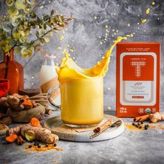 an orange juice is being poured into a glass with ingredients surrounding it on a table