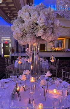 the centerpieces are filled with white flowers and lit candles for an elegant wedding reception