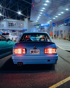 a blue car parked in an airport parking lot next to other cars on the road