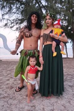 three people dressed up as hula dancers and one is holding a baby in his arms