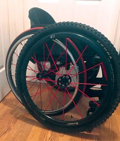 a wheel chair that is sitting on the floor in front of a door with red spokes