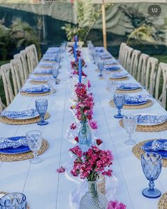 a long table set with blue and white plates, vases filled with pink flowers