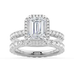 an emerald cut engagement ring set with diamonds on the band and side stones in white gold