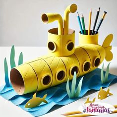 a yellow submarine made out of toilet paper next to pencils and markers on a table