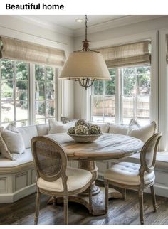 a dining room table with four chairs and a bench in front of the bay window