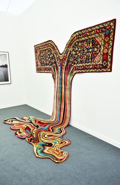 an art piece is on display in a white walled room with carpeted flooring