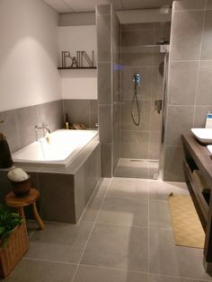 a bathroom with a walk in shower next to a sink and bathtub, surrounded by tiled walls