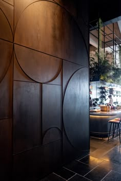 the interior of a restaurant with tables and stools in front of a large wooden paneled wall