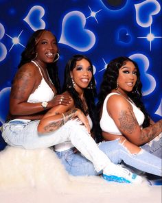 three beautiful women sitting next to each other in front of a blue background with hearts