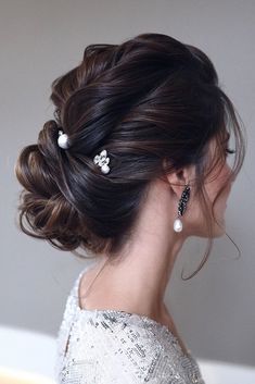 a woman with her hair up in a low bun and pearls on the top of her head