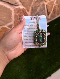 a person holding up a card with a beaded necklace on it's back