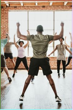 a group of people in a dance class with their arms up and hands out to the side