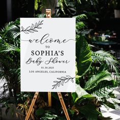 a welcome sign sitting on top of a wooden easel in front of some plants