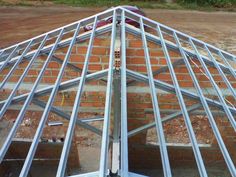 the roof of a house being constructed with metal bars on it's sides and an orange brick wall in the background