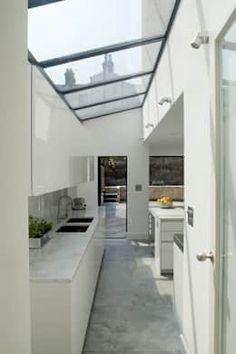 an open kitchen and dining area with skylights on the ceiling, along with white cabinets and counter tops