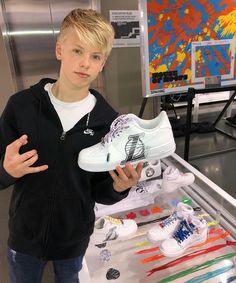 a young boy is standing in front of an assortment of shoes