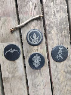 four black stone coasters sitting on top of a wooden table next to a tree branch