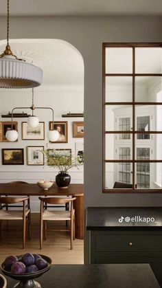 a dining room table with chairs and pictures on the wall behind it in an archway