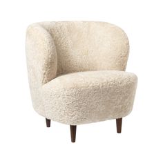 a white chair with wooden legs and a sheepskin upholstered armrests