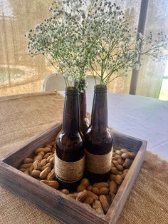 two brown bottles with flowers in them sitting on top of a table filled with nuts