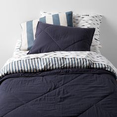 an unmade bed with blue and white pillows