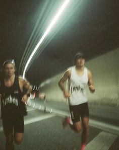 two men are running in the tunnel at night