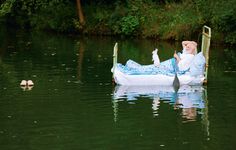 an old woman is floating on a boat in the water with two small ducks nearby