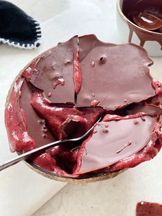 a close up of a bowl of cake with chocolate frosting on it and a spoon