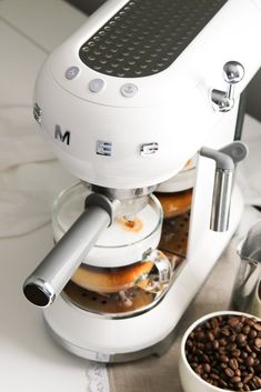 an espresso machine sitting on top of a counter next to a bowl of coffee beans